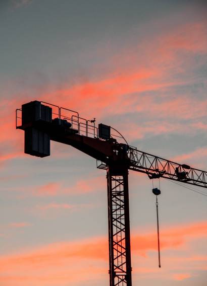 A vertical shot of an industrial construction crane during sunset